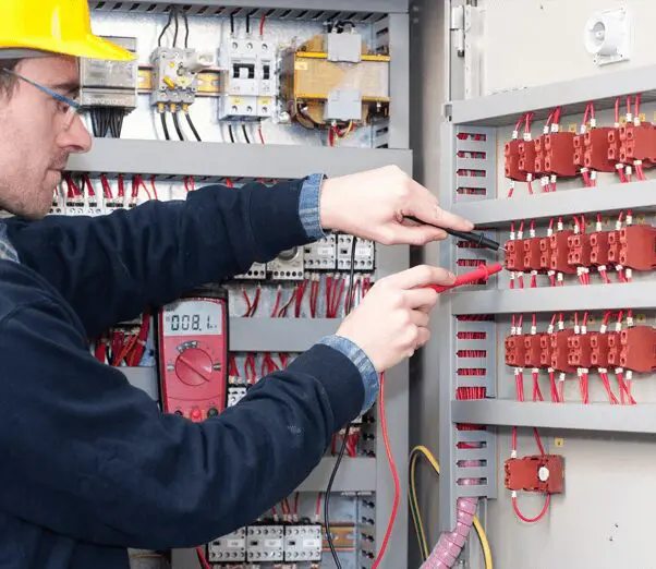 Young electrician testing industrial machine