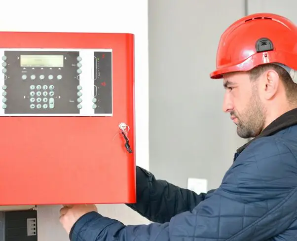 Young attractive electrical engineer at work with a red helmet on his head